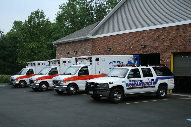 A line of New City volunteer ambulances and a
                      Rockland Paramedics vehicle parked outside the
                      station.